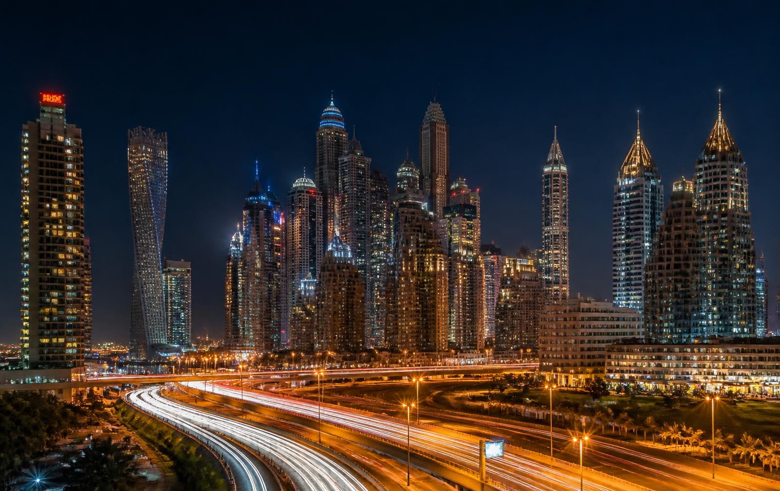 Dubai Marina skyline at night with car light trails on the highway